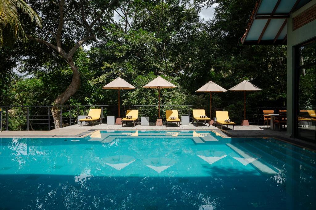 een zwembad met stoelen, tafels en parasols bij Arika Villa - Special Deals on F&B and Spa Treatments in Dambulla