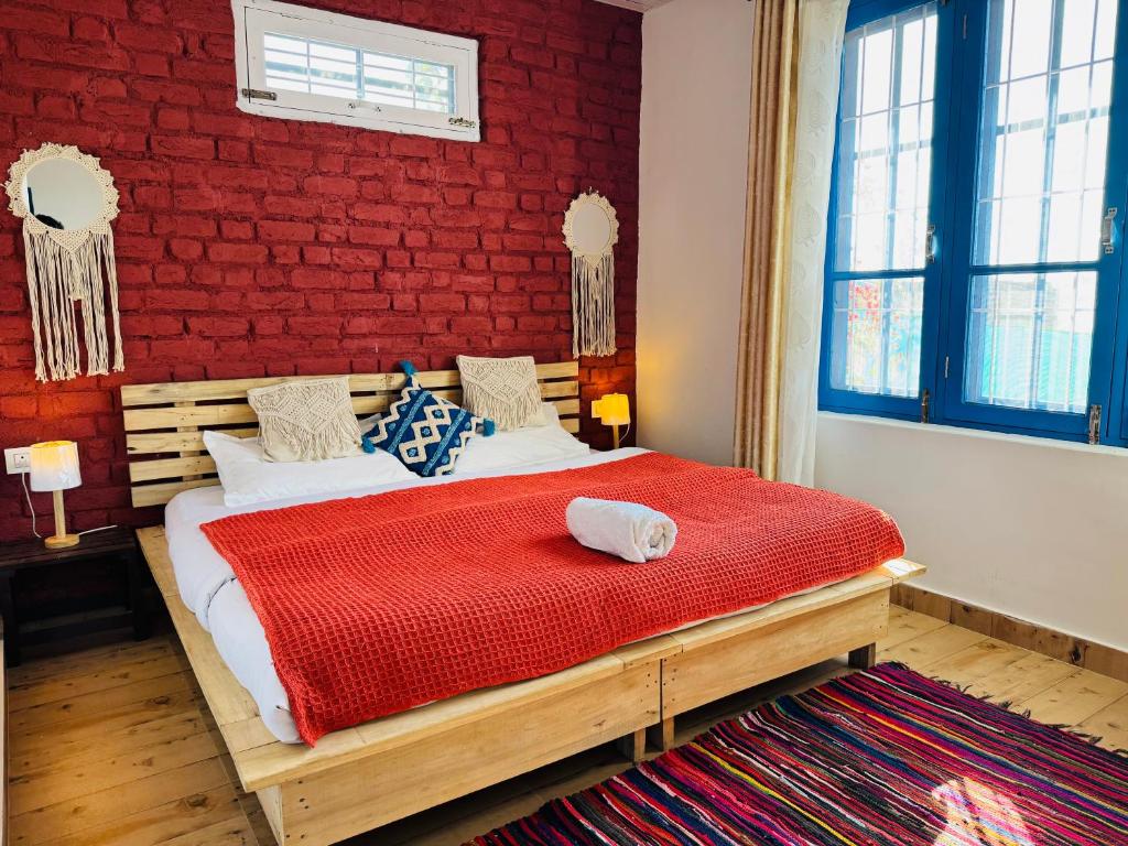 a bedroom with a bed with a red brick wall at Rishi Casa Blu, Private Villa 15 min from Paragliding point in Bīr