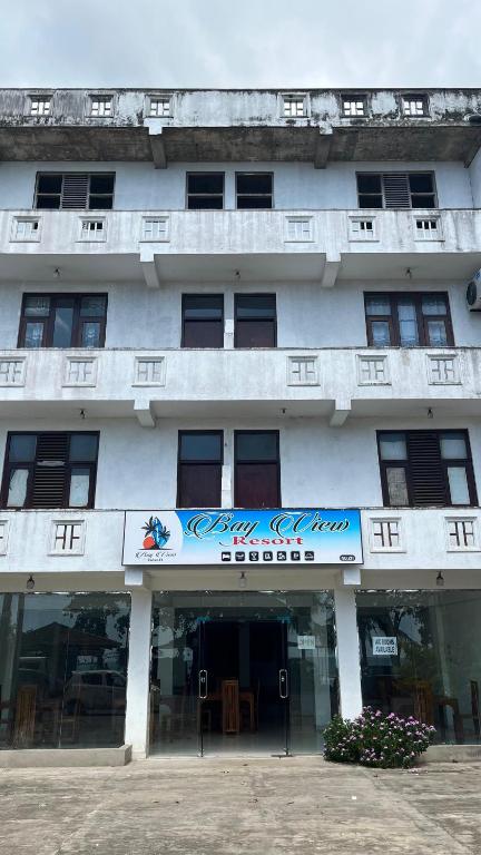 a white building with a sign on the front of it at Bayview resort in Weligama