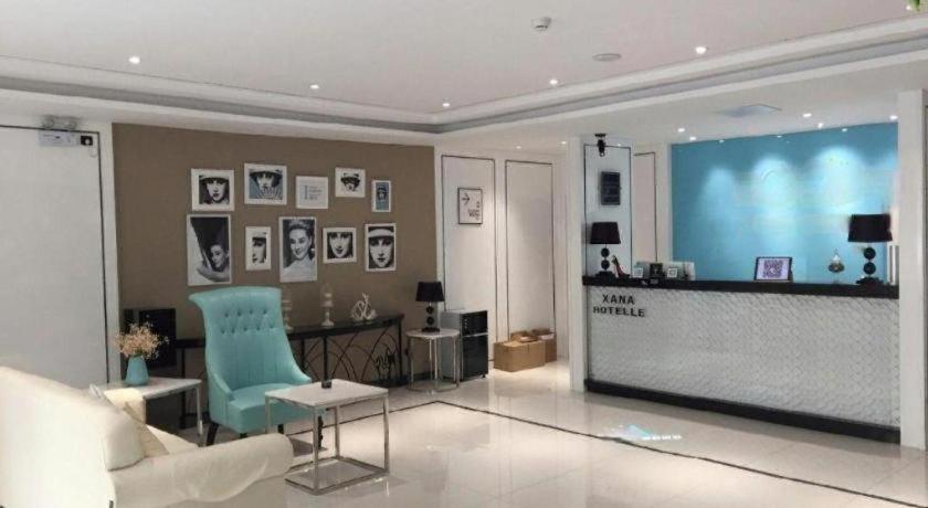 a living room with a blue chair and a large screen at Xana Hotelle· Tianjin Railway Station Jinwan Square Binjiang Avenue in Tianjin