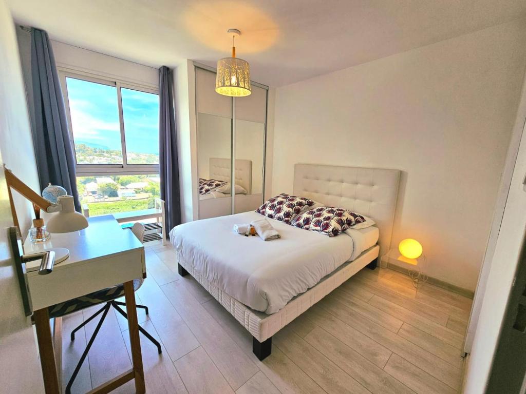 a bedroom with a bed and a desk and a window at Horizon Magellan - Grand T3 de 86m2 - Sainte-Marie in Sainte-Marie