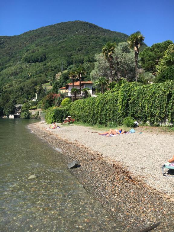 a group of people laying on a beach next to the water at Lario View Apartment in Acquaseria