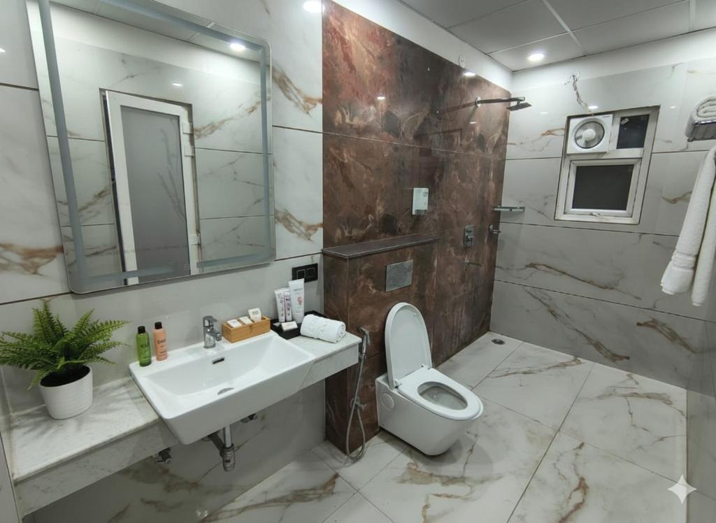 Un baño con inodoro, lavabo y espejo. en Expo Residency Inn, en Jāmb