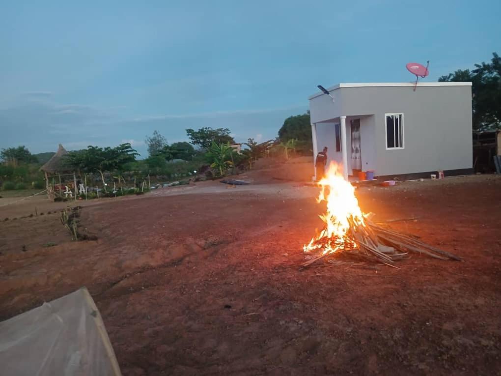 a man standing around a fire on a dirt road at Makucha Ya Simba Homestay and camping grounds in mwanza 
