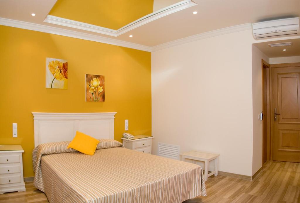 - une chambre avec un lit et un mur jaune dans l'établissement Hotel los Girasoles, à Valencina de la Concepción