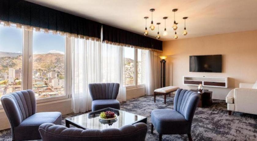 Una sala de estar con un sofá y sillas y un televisor. en Hotel Honduras Maya, en Tegucigalpa