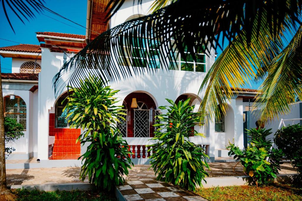 a white house with palm trees in front of it at Roots and Waves in Zanzibar City