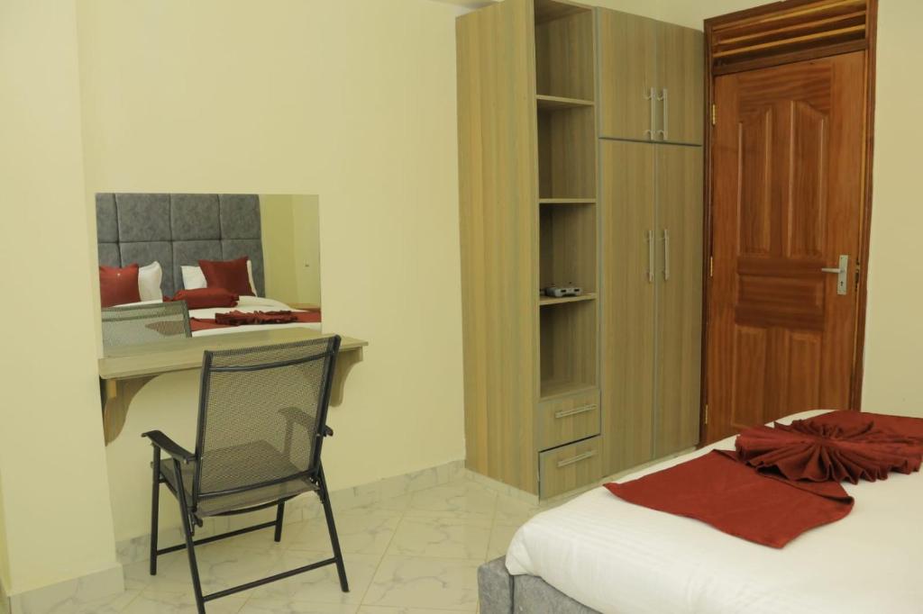 ein Schlafzimmer mit einem Bett, einem Schreibtisch und einem Stuhl in der Unterkunft Downtown Retreat Homes in Kisii