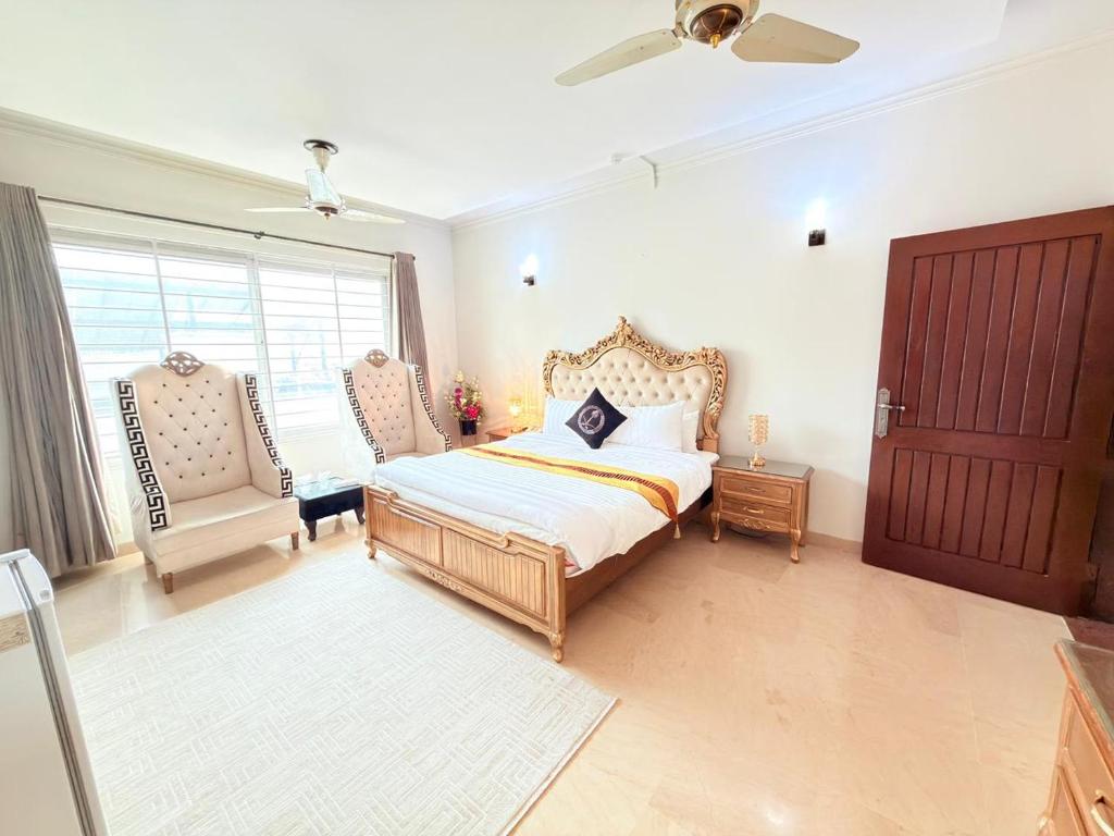 a bedroom with a bed and a chair and a window at MELBERRY Guest House in Islamabad