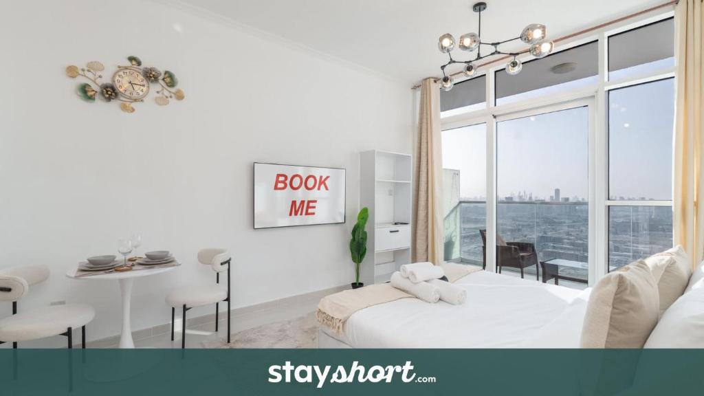 a white room with a bed and a table and chairs at StayShort - Beautifully Furnished Studio with Skyline Views in Dubai Marina