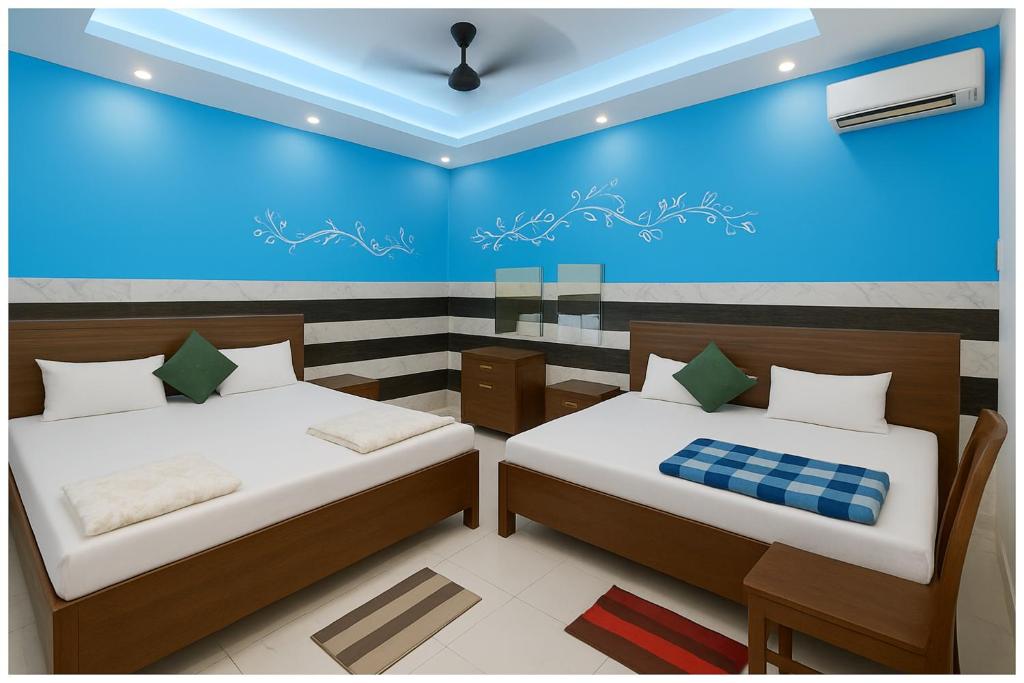 duas camas em um quarto com uma parede azul em Ayodhya The Kanha- Shiva Homestay Near Parking and Free Wifi Facility - Fully Air conditioning Comfortable Room - Best Budget Homestay IN Ayodhya em Ayodhya