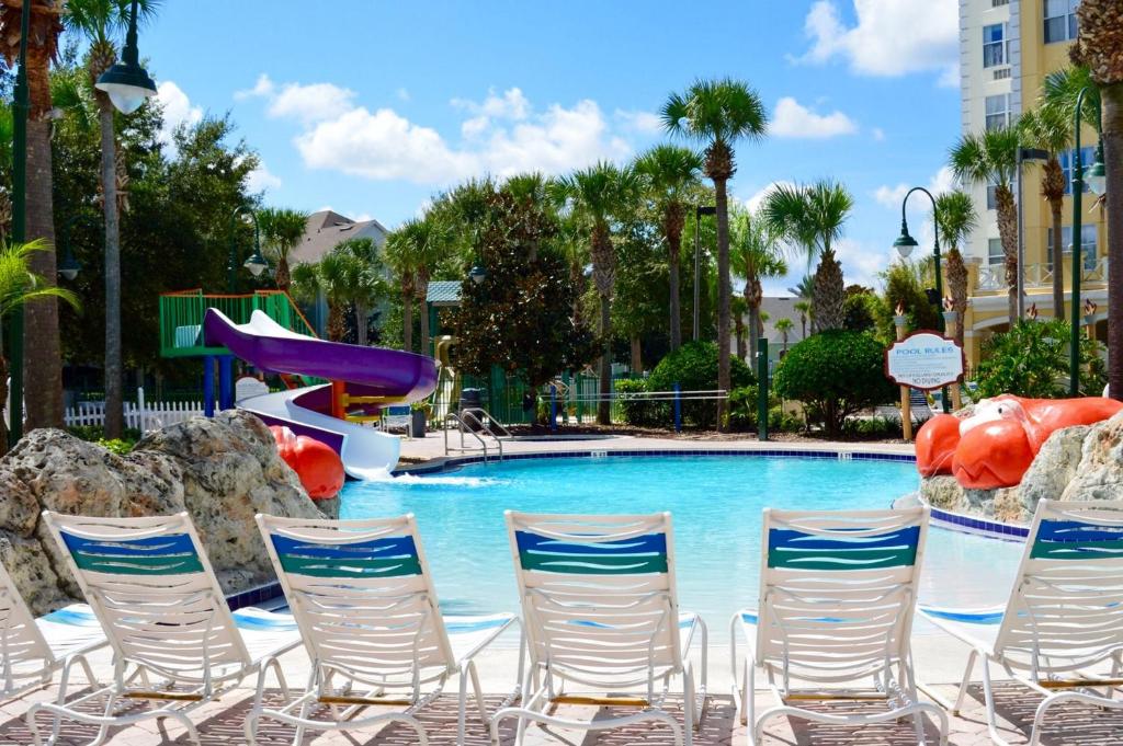 a swimming pool with chairs and a slide at Calypso Cay Vacation Villas in Kissimmee