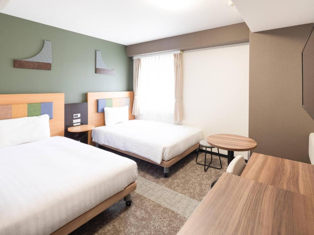 a hotel room with two beds and a table at Comfort Hotel Narita in Narita