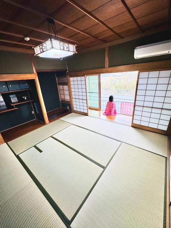 a woman sitting in a room looking out the window at ゲストハウス輪 高野山麓 in Hashimoto