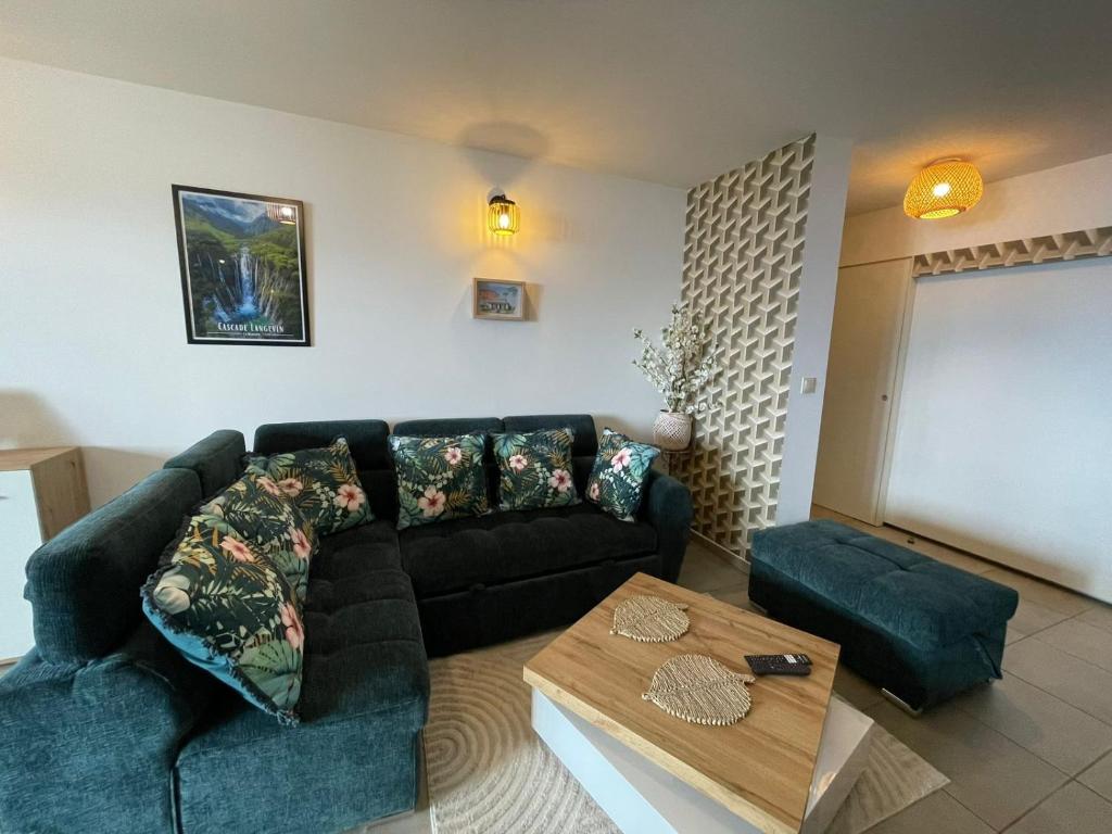 a living room with a black couch and a table at T3 Rosa - 59m2 avec piscine commune - Saint-Leu in Saint-Leu