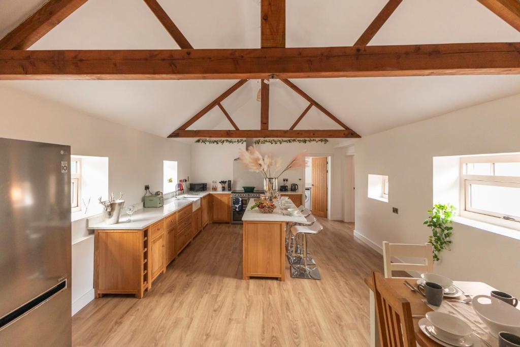 an open kitchen with wooden floors and wooden beams at Stunning 5-bed Barn Conversion in Newark-on-Trent by Renzo, Beautiful Surroundings, Sleeps 10! in Besthorpe