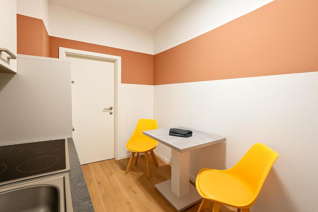 a small kitchen with two yellow chairs and a table at Moderne 3-Zimmer-Ferienwohnung in Emersleben in Halberstadt