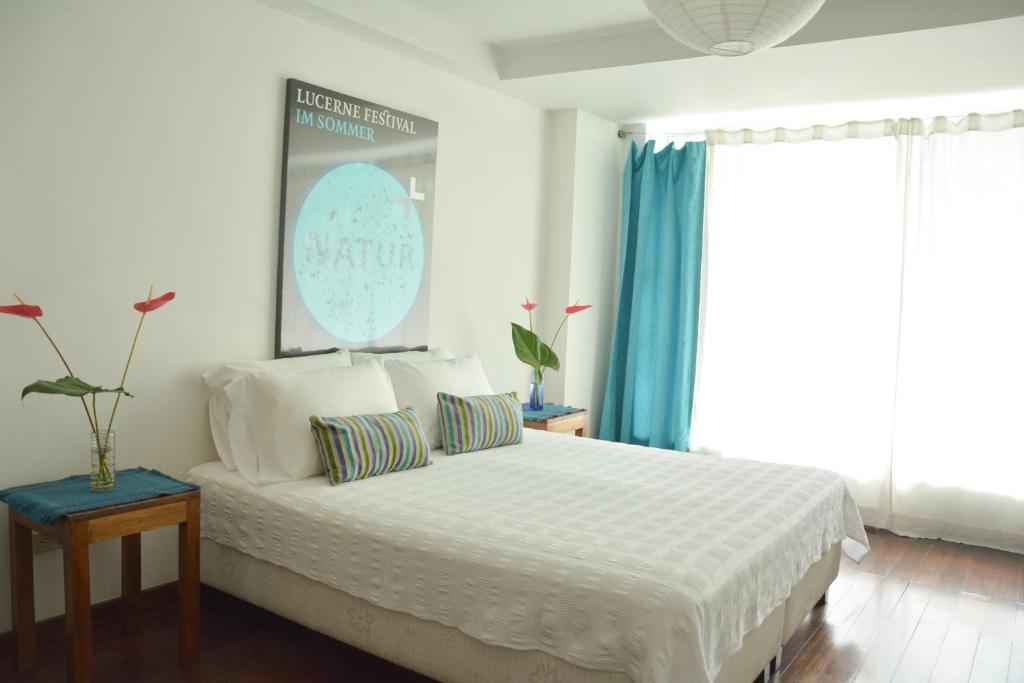 a bedroom with a white bed with blue curtains at Casa Hotel Jardin Azul in Cali