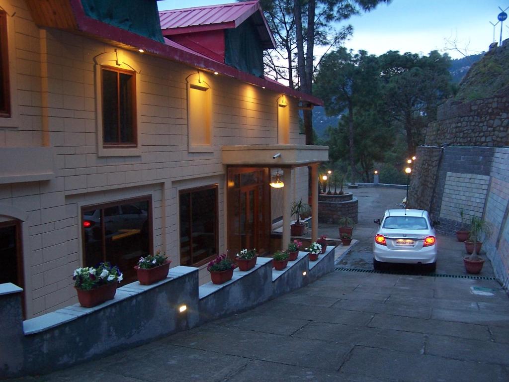 a car parked in front of a building at Forest Ville Hotel & Resort in Kasauli
