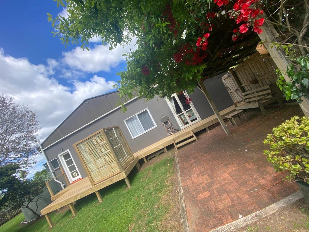 a house with a porch and benches in front of it at The Nook - Kerikeri in Kerikeri
