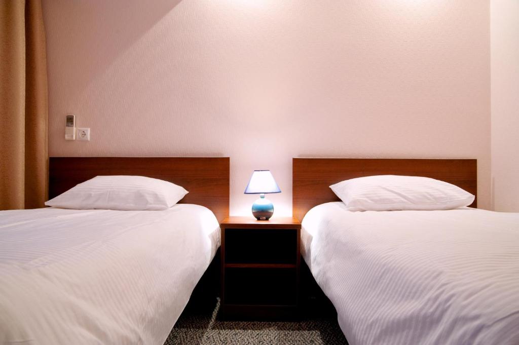 a room with two beds and a lamp on a table at Hotel Nadezhda in Nakhodka