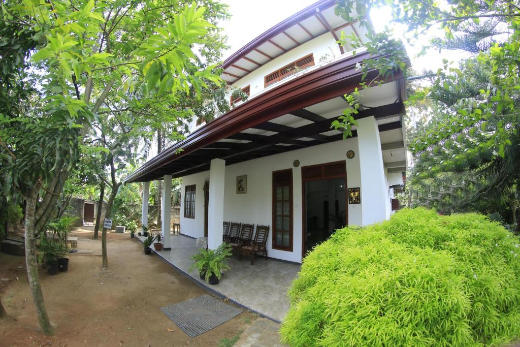 a small white house with a porch and trees at Grindlays Villa in Weligama