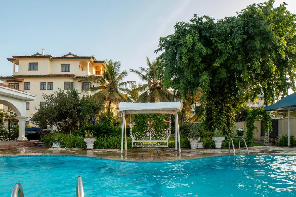a swimming pool with a gazebo in front of a building at Cosy 1 BR with Swimming Pool & Garden & 25 Mins to Airport - C04 in Mombasa
