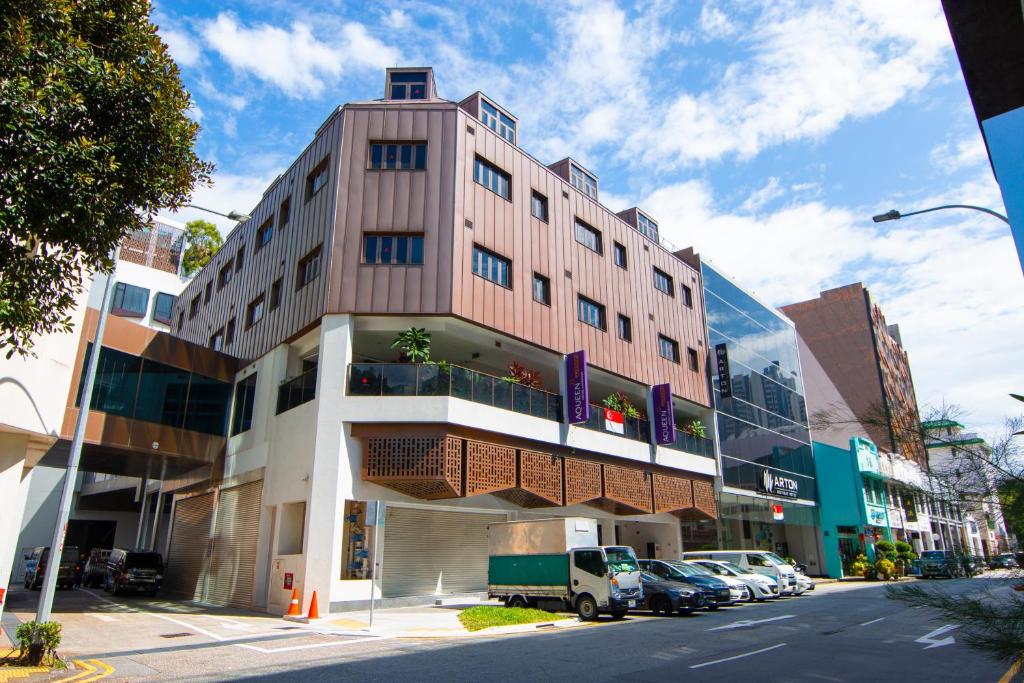 a tall building on a city street with cars parked at Aqueen Prestige Hotel Lavender in Singapore