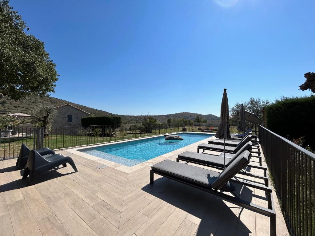 a swimming pool with two lounge chairs and an umbrella at Mas de Veyras - Gîtes 5 étoiles en Ardèche in Lachapelle Sous Aubenas