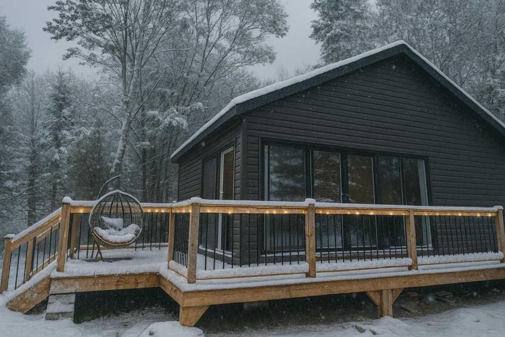 una baita nella neve con una sedia su un ponte di Lakefront Studio Cottage #8 a Dillon