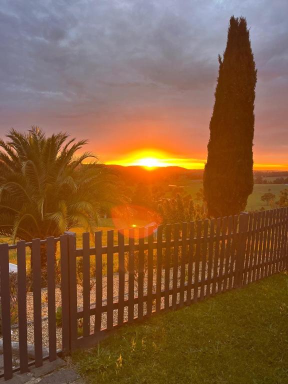 a sunset behind a white fence with a tree at The Bloom Farm Cottage in Carrajung South