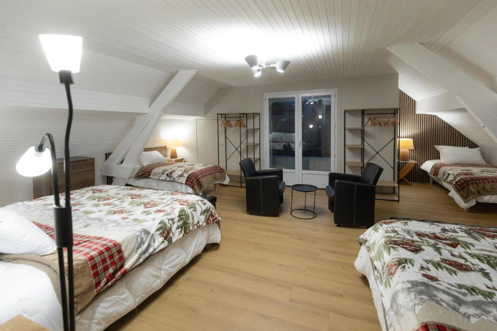 a attic room with two beds and two chairs at Le Refuge des Isards - Chalet familial in Cauterets