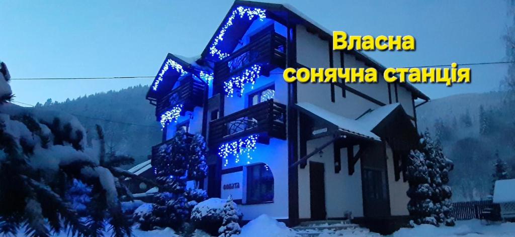 un edificio con luces azules en la nieve en Villa Girska Sonata, en Mykulychyn