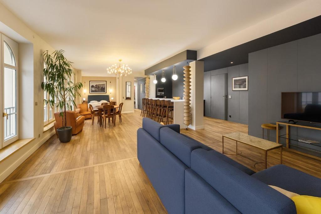 een woonkamer met een blauwe bank en een eetkamer bij Loft me - Entre art deco et loft à l'americaine in Périgueux