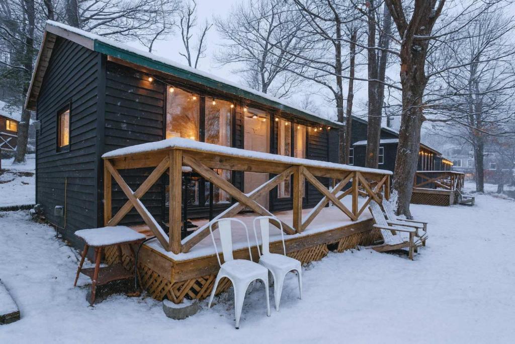 a cabin with two chairs and a porch in the snow at Studio Cottage #9 - Virginia Pine in Gravenhurst