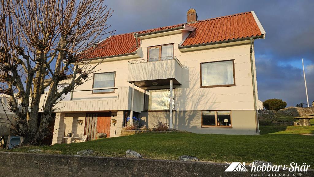 House near the sea and town centre in Skärhamn SE09107 في Nordvik: بيت ابيض كبير بسقف احمر