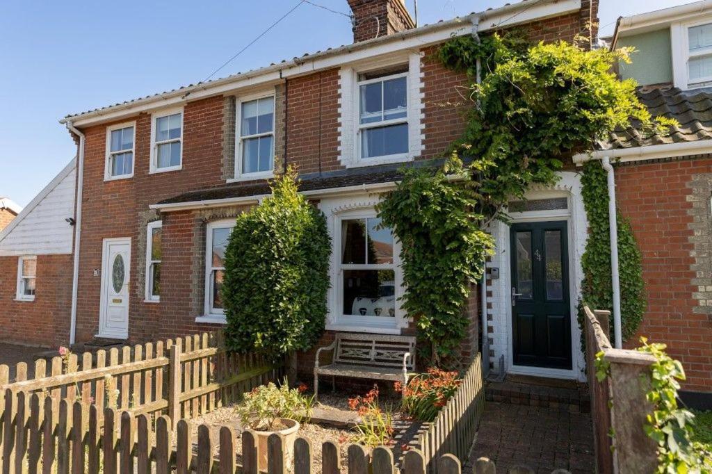 a brick house with a wooden fence in front of it at Australis, a charming and cosy cottage in Southwold in Reydon