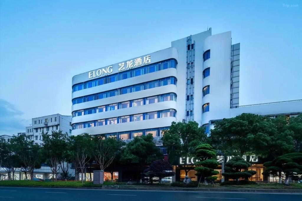 un grand bâtiment blanc avec une enseigne dessus dans l'établissement eLong Hotel Suzhou Guanqian Street, à Suzhou