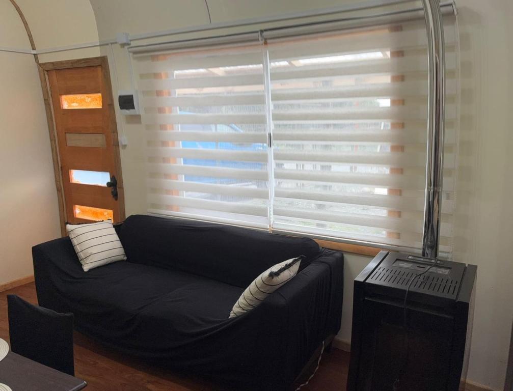 a living room with a black couch and a window at Cabaña Quellón 