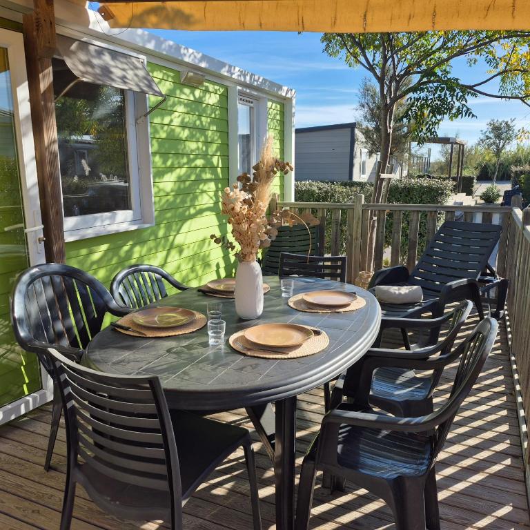 L'Oasis Mobil Home à 100m de la Plage Camping 5 étoiles في توراي: طاولة وكراسي على السطح