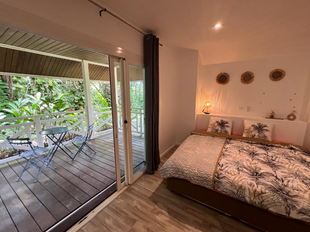 Bungalow Terra - Sarramea في Sarraméa: غرفة نوم مع سرير وبلكونة مع طاولة
