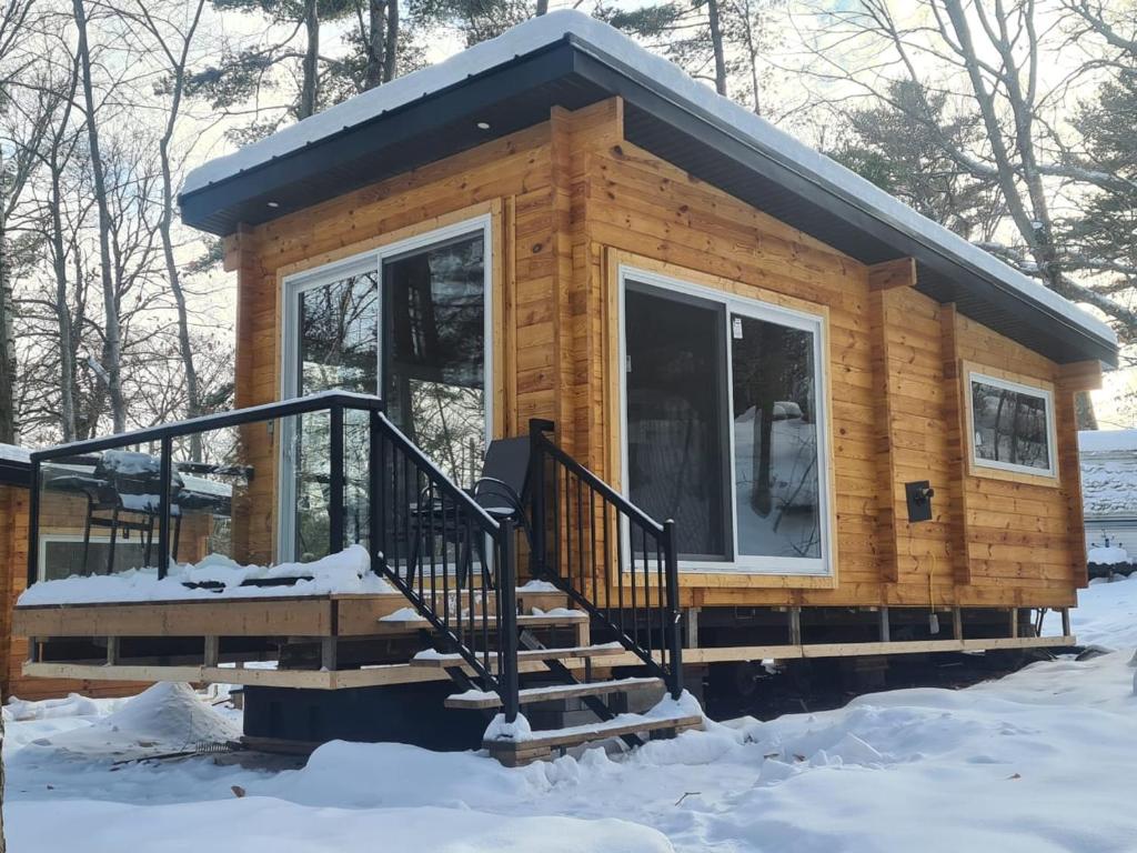 a log cabin with a porch in the snow at 1-bedroom Unique Eco Log Cabins in Parry Sound #103 in Parry Sound