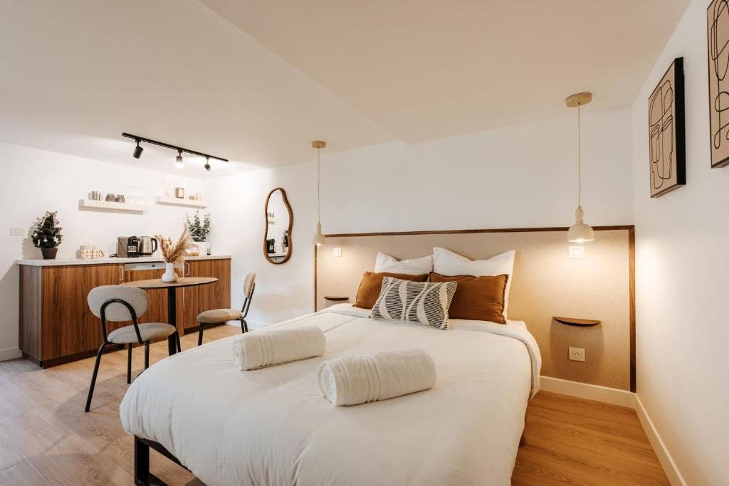 a bedroom with a large white bed and a kitchen at L'Alma- Accès Privée-Proche Aéroport-Parking-Wifi in Achenheim