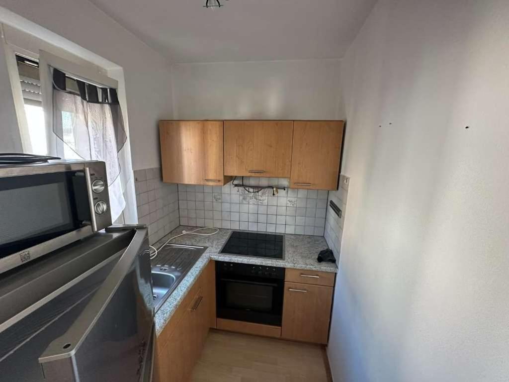una pequeña cocina con armarios de madera y microondas en Charmante 2-Zimmer-Wohnung, en Eisenstadt