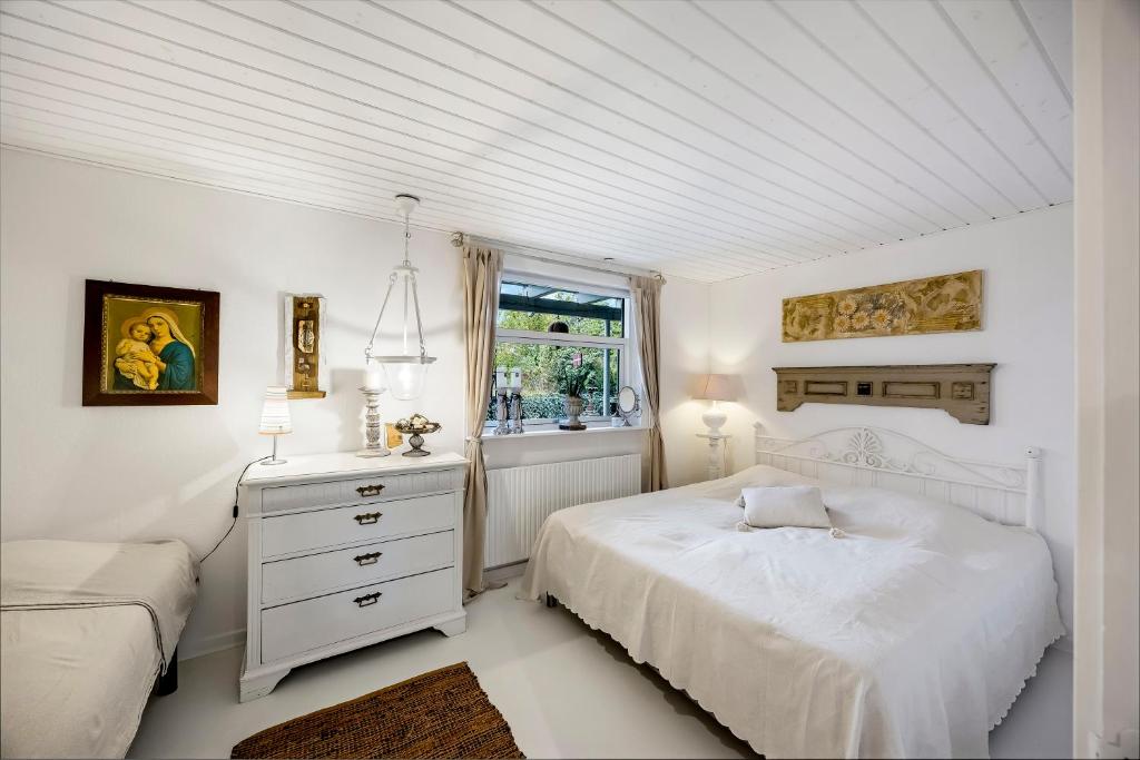a white bedroom with a bed and a window at Tina Risager bed & breakfast in Sindal