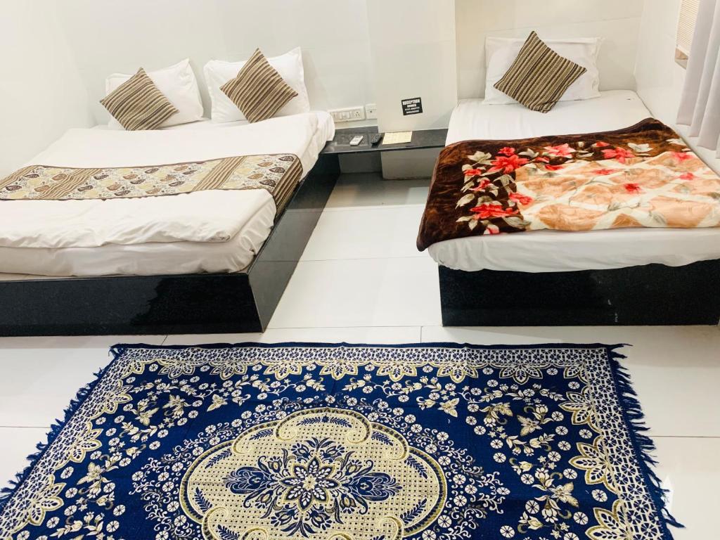 two beds in a room with a blue and white rug at Hotel Churu Palace in Jaipur