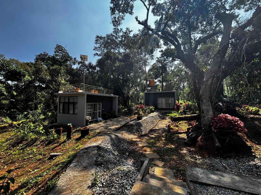 a tiny house in a garden with a tree at Calm Ville in Ponnampet
