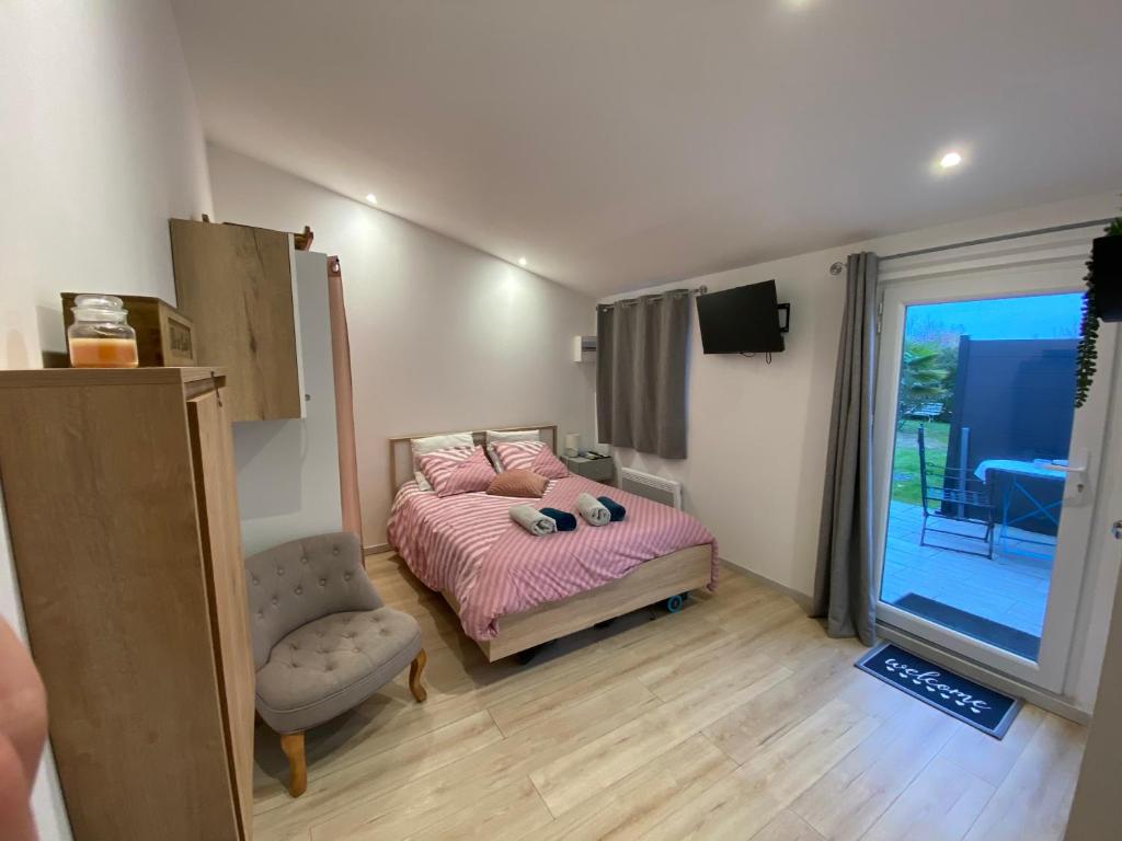 ein Schlafzimmer mit einem Bett, einem Stuhl und einem Fenster in der Unterkunft Maisonnette cosy au calme terrasse local vélo in Rochefort