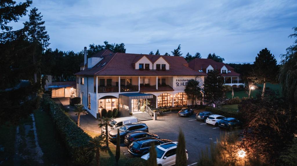 una casa grande con coches aparcados en un aparcamiento en Hotel Saint-Hubert, en Hambach