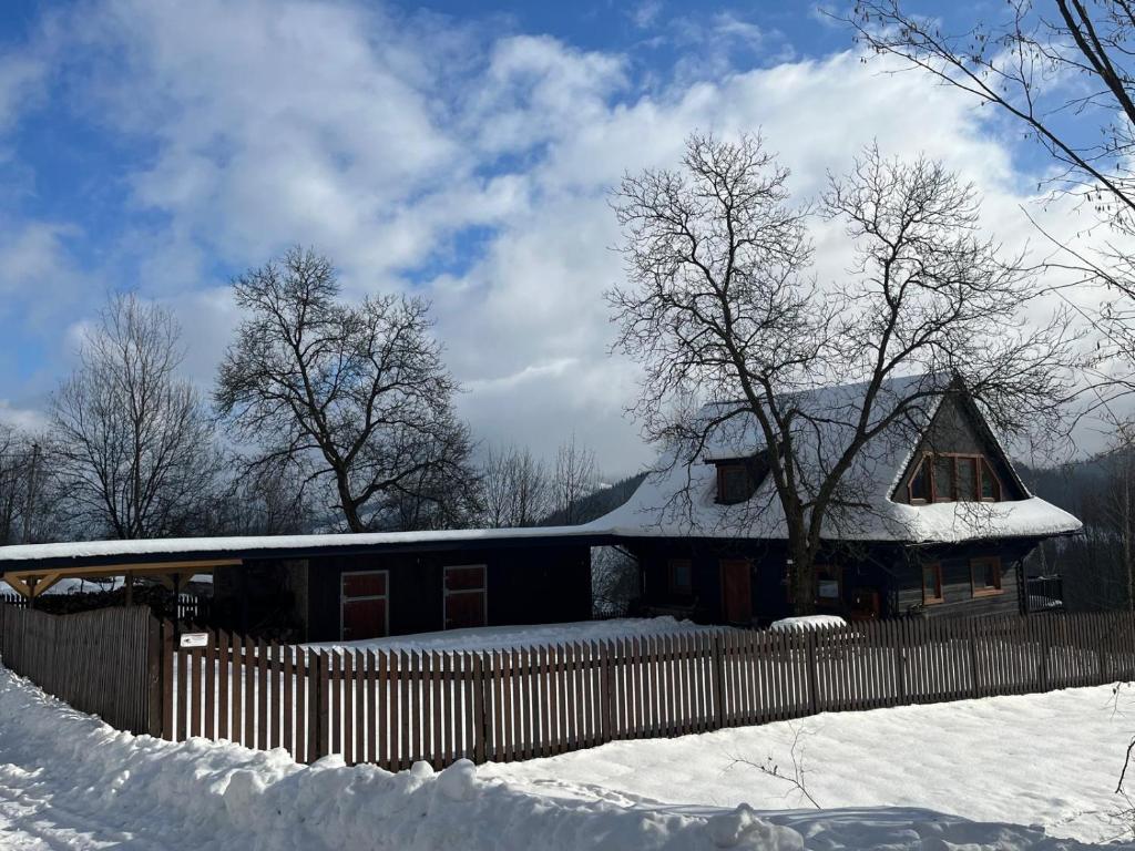 a house covered in snow with a fence at Chalupa u Golisov in Zákopčie